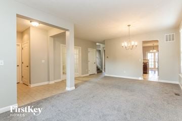 Greenwood house for rent - A spacious living room with a grey carpet and a chandelier.