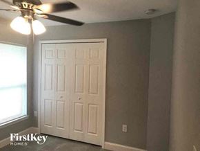 Lehigh Acres house for rent - a bedroom with a ceiling fan and a white door