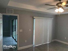 Lehigh Acres house for rent - an empty living room with a ceiling fan and a door