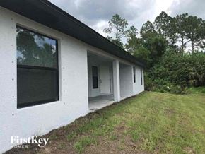 Lehigh Acres house for rent - a white house with a grass yard and trees