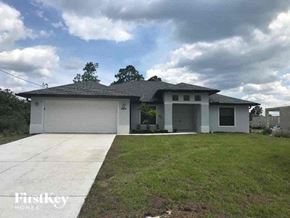 Lehigh Acres house for rent - a white house with a lawn and a driveway