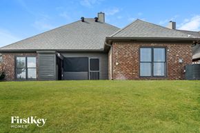 Chelsea house for rent - A house with a grey roof and a brick wall is shown with a grassy lawn in front.