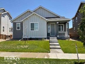Commerce City house for rent - a gray house with a porch and a lawn