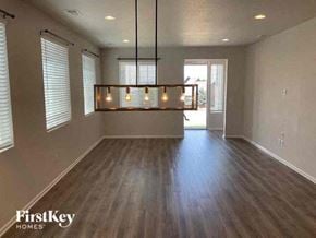Commerce City house for rent - an empty living room with wood floors and a light fixture
