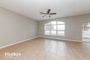 Parrish house for rent - A spacious room with a ceiling fan and large windows.