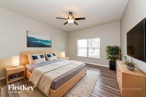Parrish house for rent - A bedroom with a bed, a ceiling fan, a painting, a potted plant, and a TV.