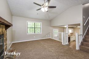Flowery Branch house for rent - an empty living room with a fireplace and a ceiling fan