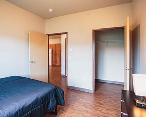Watford City apartment for rent - A bedroom with a bed, a desk, and a closet.