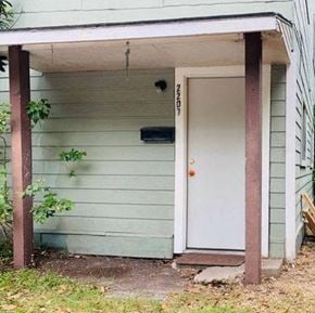 Bay City house for rent - A white door is on the right side of a small building with a porch.