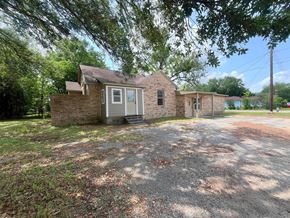 Bay City house for rent - A house with a gravel driveway and trees in the background.
