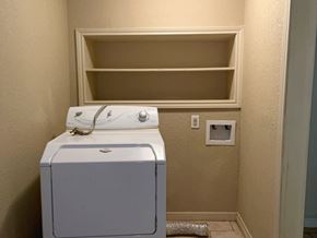Bay City house for rent - A white dryer sits next to a shelf in a room.
