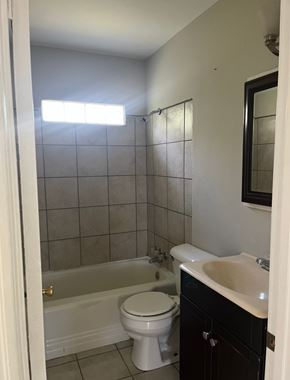Bay City house for rent - A white toilet is in a bathroom with a black cabinet.