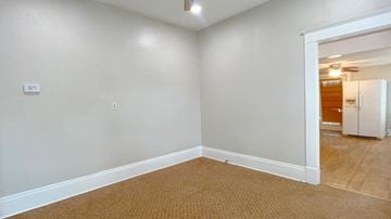 Bay City house for rent - the living room and dining room of an empty house with a door to the bathroom