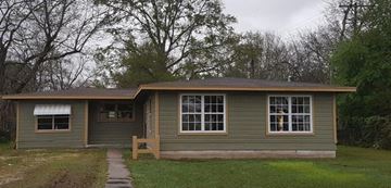 Bay City house for rent - A small house with a brown door and a brown bench in front of it.