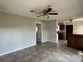 Bay City house for rent - an empty living room with a ceiling fan and a kitchen