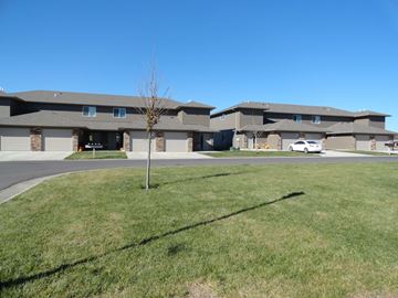 Brandon apartment for rent - A tree stands in the middle of a grassy area in front of a building.