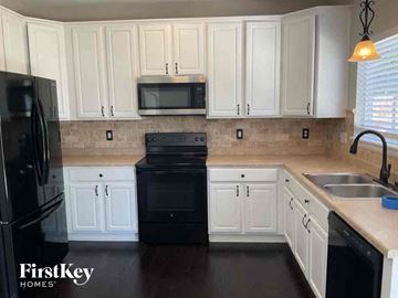 Aurora house for rent - a white kitchen with black appliances and white cabinets