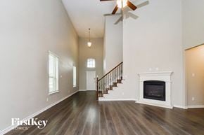 Mckinney house for rent - A spacious living room with a fireplace and a staircase.