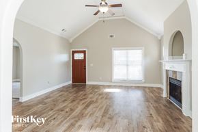 Calera house for rent - an empty living room with a fireplace and a ceiling fan