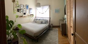 Minneapolis apartment for rent - A bedroom with a bed, a plant, and pictures on the wall.