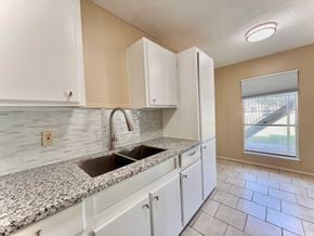 Bay City house for rent - a kitchen with white cabinets and a sink
