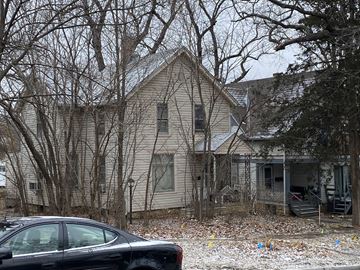 Lawrence apartment for rent - A black car is parked in front of a house with bare trees.