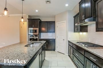 Edmond house for rent - a kitchen with black cabinets and granite counter tops and a sink