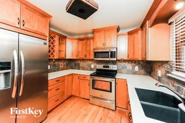 Cumming house for rent - a kitchen with wooden cabinets and stainless steel appliances