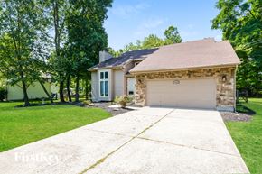 Miami Twp house for rent - A house with a garage is surrounded by trees.