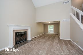 Miami Twp house for rent - A spacious living room with a fireplace and carpeted floor.