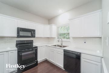 Charlotte house for rent - a white kitchen with black appliances and white cabinets