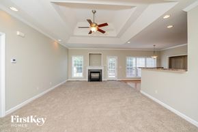 Advance house for rent - an empty living room with a fireplace and a ceiling fan