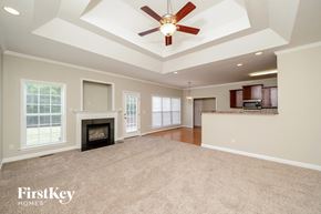 Advance house for rent - an empty living room with a fireplace and a ceiling fan