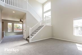 Commerce City house for rent - A spacious living room with a staircase leading to the upper floor.