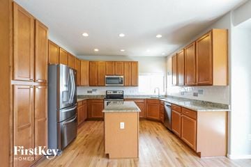 Commerce City house for rent - A kitchen with wooden cabinets and a refrigerator.