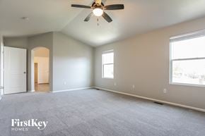 Commerce City house for rent - A spacious room with a ceiling fan and two windows.