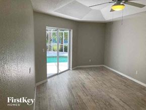 North Port house for rent - an empty living room with a sliding glass door to a pool