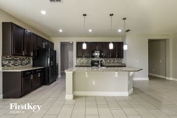 Orlando house for rent - A kitchen with black cabinets and a granite countertop.