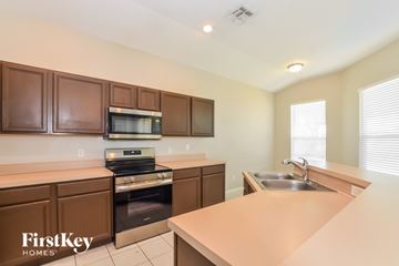 Orlando house for rent - A kitchen with brown cabinets and a stove top oven.