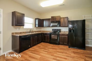 Cartersville house for rent - an empty kitchen with black appliances and wood flooring