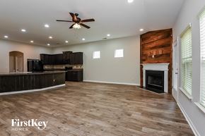 Ball Ground house for rent - A spacious living room with a fireplace and wood flooring.
