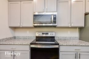 Covington house for rent - a kitchen with white cabinets and a stove and a microwave