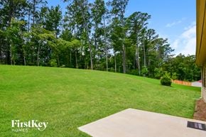 Covington house for rent - a backyard with a grass lawn and trees in the background