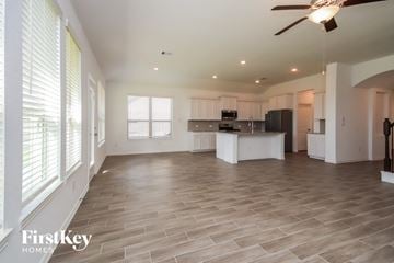 Mont Belvieu house for rent - A spacious kitchen and living room with a ceiling fan and lighting.