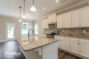 Gainesville house for rent - a kitchen with white cabinets and a granite counter top