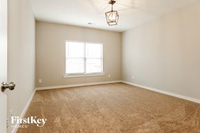 Cullman house for rent - a bedroom with carpet and a window and a light fixture