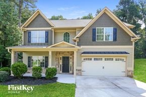 Hoschton house for rent - a beige house with a driveway and a garage door