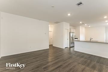 Hockley house for rent - A spacious room with wooden flooring and a kitchen area with white cabinets and a countertop.