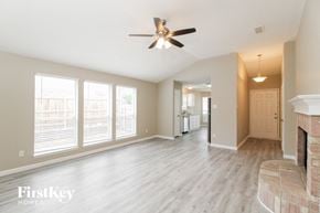 Fort Worth house for rent - A spacious living room with a fireplace and a ceiling fan.