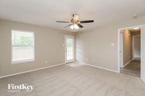 Fort Worth house for rent - A spacious room with a ceiling fan and a door leading to another room.